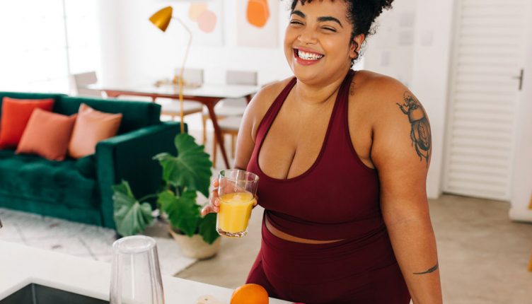 woman-blending-a-smoothie-in-a-kitchen-with-fresh-fruit-on-the-counter